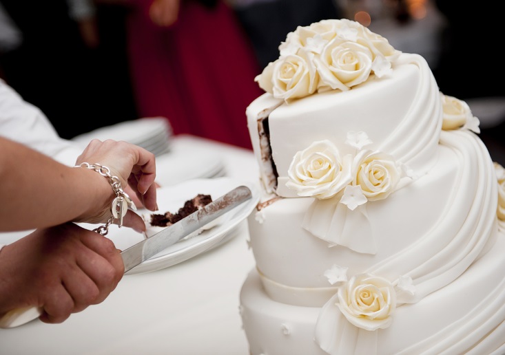 Bride and groom cutting their exquisite white and red wedding cake