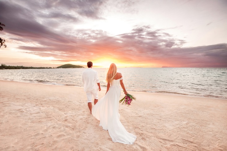 Beautiful bride and groom watching the sunset over the ocean