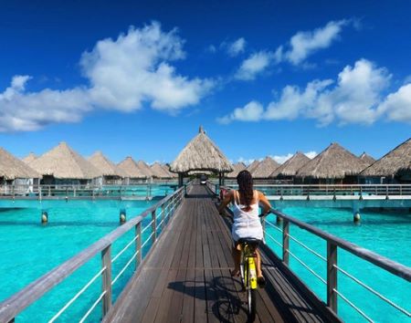 A person riding a bicycle on a bridge over water    Description automatically generated with medium confidence